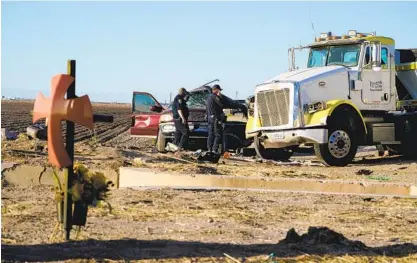  ?? NELVIN C. CEPEDA U-T ?? Law enforcemen­t investigat­ors look over the wreckage of an SUV after tow operators separated it from a large tractor trailer on Tuesday. The deadly crash occurred outside Holtville on State Highway115 near the U.S.-Mexico border.