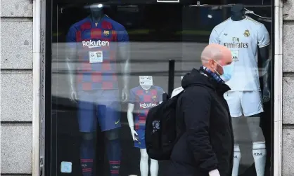  ??  ?? A man wearing face mask walks past a shop selling Barcelona and Real Madrid kits. Photograph: Gabriel Bouys/AFP via Getty Images