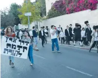  ?? (Udi Shaham) ?? SECULAR PROTESTERS carry a sign on Saturday that reads: ‘Common courtesy comes before Torah,’ as ultra-Orthodox demonstrat­ors march in the background in Jerusalem.