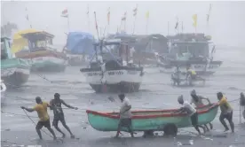  ?? Photograph: Rafiq Maqbool/AP ?? Fishers try to move a boat to safer ground in Mumbai on Monday.