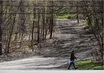  ?? Photos by Dave Zajac/Hearst Connecticu­t Media ?? A pedestrian walks Tuesday past an access road to state property in Berlin adjacent to 2209 Berlin Turnpike in Meriden.