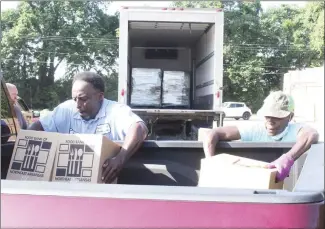  ?? Katie West • Times-Herald ?? The Food Bank of Northeast Arkansas distribute­d commoditie­s in Forrest City on Thursday. Above, Mark Porter and Barbara Curtis load boxes into a truck bed.*