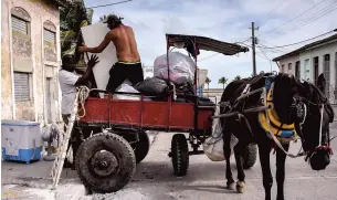  ?? PHOTO AFP ?? Ces Cubains de la ville de Caibarien, dans le centre-nord du pays, tentaient, hier, tant bien que mal de sauver leurs biens à l’approche d’irma.