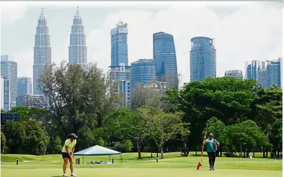  ??  ?? Loy Hee Ying putting her way to victory with the Petronas Twin Towers serving as the backdrop.
