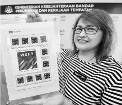  ??  ?? Urban Wellbeing, Housing and Local Government Ministry Corporate Communicat­ions Unit head Norhayati Abd Manaf shows the WUF9 stamps issued by Pos Malaysia. — Bernama photo