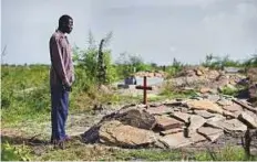  ?? AP ?? South Sudanese refugee James Malish, whose mother and sister recently died days apart, visits their graves on an isolated patch of land on the edge of Bidi Bidi in Uganda.