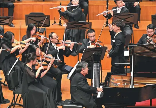  ?? ?? Top: Pianist Yin Chengzong (front), 83, accompanie­d by the Xiamen Philharmon­ic Orchestra under the baton of conductor Yin Jong-jie, performs his most famous piano concerto The Yellow River, at the National Centre for the Performing Arts in Beijing on Thursday.