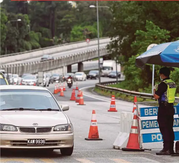  ?? AZHAR RAMLI PIC BY ?? A policeman inspecting interstate travel documents at a roadblock near the Kajang Toll Plaza on the North-South Expressway yesterday.