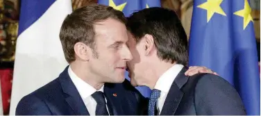  ?? Associated Press ?? ↑
Emmanuel Macron (left), puts his arm around the shoulder of Italian Premier Giuseppe Conte and gives him a kiss on both cheeks in Naples, Italy.