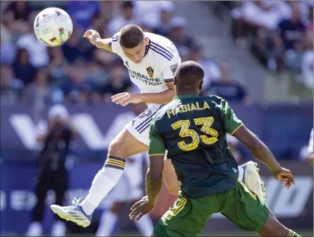  ?? ALEX GALLARDO – THE ASSOCIATED PRESS ?? Galaxy forward Dejan Joveljic, left, heads the ball for a game-tying goal past Portland Timbers defender Larrys Mabiala in the 88th minute Saturday.