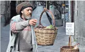  ??  ?? A man appears at a food basket put up in the street in an increasing­ly impoverish­ed Italy. The sign reads: ‘Those who can put in; those who can’t take out’