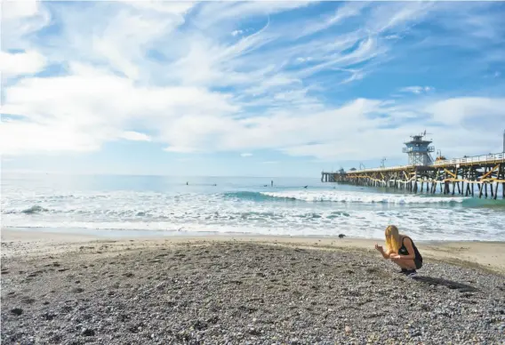  ?? Stuart Palley / Special to The Chronicle ?? Chanel Juzaitis, one of Kevin Sherbondy’s daughters, hunts for sea glass near the San Clemente Pier. She and her twin sister, Cheyenne, live near their mother.