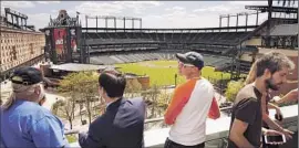  ?? Carolyn Cole. Los Angeles Times ?? A FEW FANS gather beyond the walls of Baltimore’s Camden Yards, but none were allowed inside for the Orioles’ win over the White Sox, for security reasons.