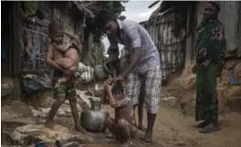  ?? SERGEY PONOMAREV/THE NEW YORK TIMES ?? A Rogingya man bathes his child at the Kutupalong Refugee Camp in Bangladesh. Many Rohingya fleeing the Burmese army seek human trafficker­s in Bangladesh.