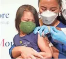  ?? MARY ALTAFFER/AP FILE ?? Maria Assisi holds her daughter Mia, 4, as the Moderna COVID-19 vaccine is administer­ed last month in New York.