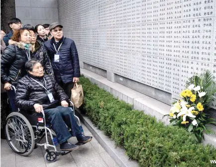  ??  ?? Family members of victims in Nanjing Massacre watch newly added names on the wall at the Memorial Hall of the Victims in Nanjing Massacre by Japanese Invaders in Nanjing.