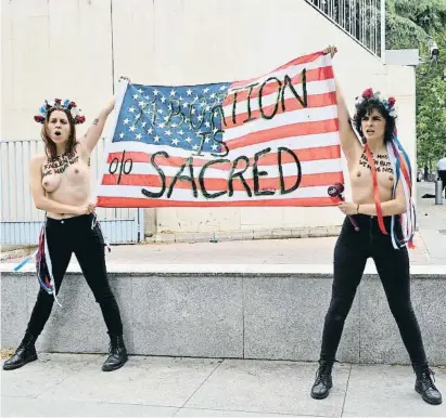  ?? Mustavo Valiente / EP ?? Dos integrante­s de Femen con una bandera de EE.UU. en una protesta ante la embajada en Madrid