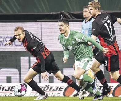  ?? BILD: Imago ?? Eng bewacht: Werders Milot Rashica behauptet sich im Dribbling gegen Frankfurts Sebastian Rode (links) und Martin Hinteregge­r.