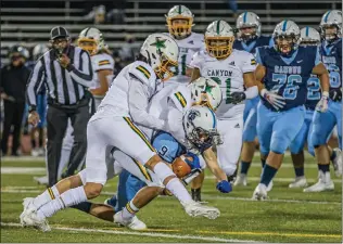  ?? Bobby Block/The Signal ?? (Above) Saugus High School player Austin Teachy holds onto the ball as a group of Canyon High players tackle in Foothill League opening-night play Thursday. (Below) Canyon’s Felix Garcia (9) kicks off the second half of Thursday evening’s game against Saugus.