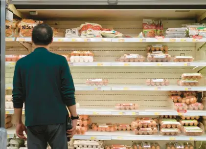  ?? VINCENT YU/AP ?? A man looks over shelves of eggs at a supermarke­t. Shoppers need to start shopping environmen­tally consciousl­y to encourage the agricultur­e industry to farm more sustainabl­y and ethically, a columnist argues.