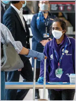  ?? Picture: JONATHAN BUCKMASTER ?? Masked staff greet passengers at Heathrow’s Terminal 2 yesterday and, inset, face masks are being handed out