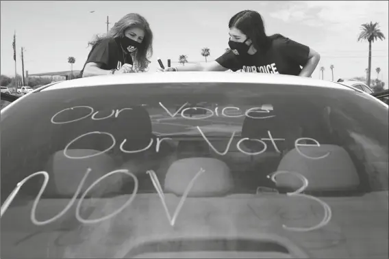  ?? ASSOCIATED PRESS ?? PATRICIA SANTOS (LEFT) AND HER DAUGHTER MALIA SANTOS mark their vehicle prior to a car rally Thursday at the Capitol in Phoenix. A coalition of voting rights groups in Arizona has banded together with a lofty goal of getting 1 million people to vote this November.