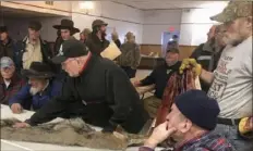  ?? Michael Hill/Associated Press ?? Potential buyers examine a coyote pelt on a table at the trappers' auction.