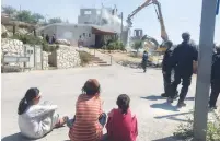  ?? (Seth J. Frantzman) ?? SETTLER CHILDREN and Border Police officers watch as a crane begins demolishin­g two illegal buildings in Beit El yesterday.