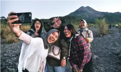  ?? PHOTOS BY SLAMET RIYADI ASSOCIATED PRESS ?? LEFT: Local tourists take a selfie Aug. 6 in front Mount Merapi, in Yogyakarta, Indonesia. The temple and nearby Yogyakarta are among 10 sites earmarked for developmen­t to attract more tourists.