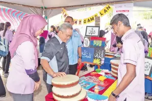  ??  ?? HASNOL (dua dari kiri) mengunjung­i gerai pameran yang berlangsun­g pada karnival berkenaan.