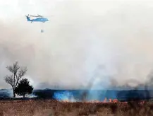  ?? [PHOTOS BY SARAH PHIPPS, THE OKLAHOMAN] ?? An Army National Guard helicopter brings water to a wildfire Sunday in southeast Oklahoma City.