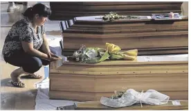  ?? GREGORIO BORGIA / ASSOCIATED PRESS ?? A woman inside a gymnasium in Ascoli Piceno, Italy, touches a coffin Friday containing one of the victims of Wednesday’s earthquake in the central part of the country. The gym has 34 caskets lined up for a funeral Mass today.