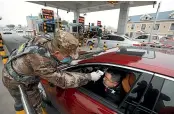  ?? AP ?? A militia member uses a digital thermomete­r to take a driver’s temperatur­e at a checkpoint at a highway toll gate in Wuhan.