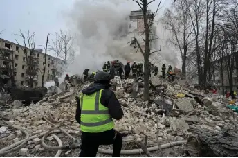  ?? — AFP photo ?? Ukrainian rescue workers clear debris at the site of a missile attack in Kharkiv.