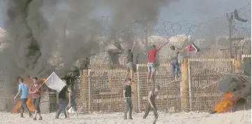  ?? — AFP photo ?? Palestinia­n protestors climb a fence separating them from Israeli security forces during demonstrat­ion on the beach near the maritime border with Israel, in the northern Gaza Strip.