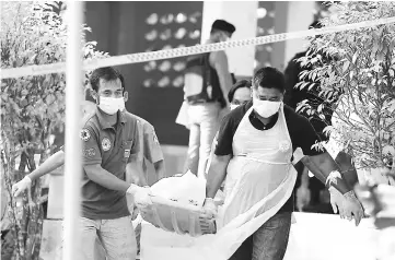  ?? — AFP photo ?? Paramedics take away a body after four Thai civil defence volunteers were shot and killed outside of a school in the restive southern province of Pattani.