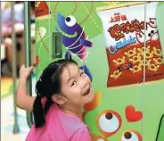  ?? LI LONG / FOR CHINA DAILY ?? A child stands in front of an Oishi snack food poster in Nanchang, Jiangxi province.