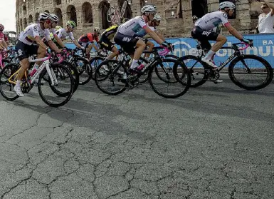  ??  ?? Al Colosseo A sinistra il passaggio dei ciclisti fotografat­i da una folla di appassiona­ti, ieri pomeriggio all’altezza dell’Anfiteatro Flavio. Sopra un’immagine dell’asfalto rovinato e sconnesso (foto LaPresse)