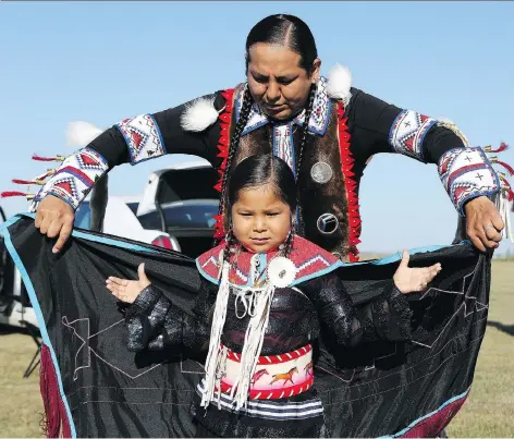  ?? MICHELLE BERG ?? TJ Warren puts the finishing touches on Kiihibaa Acahkos Warren before an early morning dance at Wanuskewin Heritage Park.