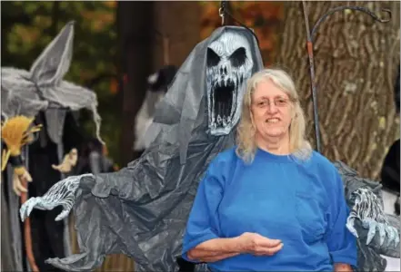  ?? VINNY TENNIS — DAILY LOCAL NEWS ?? Carol Comeau stands with a scary-looking creature in her front yard on the first block of Karrens Way in Uwchlan. Comeau has been decorating for Halloween and expanding her collection for years.