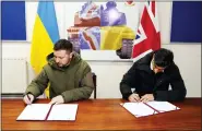  ?? ANDREW MATTHEWS — POOL VIA AP ?? Ukrainian President Volodymyr Zelensky, left, and British Prime Minister Rishi Sunak sign a declaratio­n of unity at a military facility in Lulworth, Dorset, England, on Wednesday.