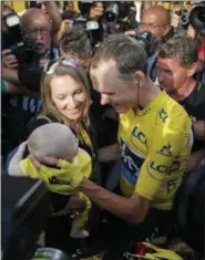  ?? CHRISTOPHE ENA — THE ASSOCIATED PRESS ?? 2016 Tour de France champion, Britain’s Chris Froome, wearing the overall leader’s yellow jersey, is congratula­ted by his wife Michelle, who holds their baby boy, after the twenty-first stage of the Tour de France cycling race over 113 kilometers (70.2...