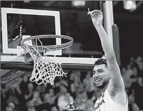  ?? AP/STEVE HELBER ?? Virginia guard Ty Jerome holds a piece of the net after the Cavaliers came back to beat Louisville.