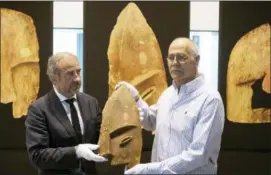  ?? RALF HIRSCHBERG­ER — DPA VIA AP ?? John Johnson, right, of the Chugach Alaska Corporatio­n and Hermann Parzinger, left, President of the Prussian Cultural Heritage Foundation, show a historical wooden item, plundered from the graves of indigenous Alaskans, during a ceremony at the...