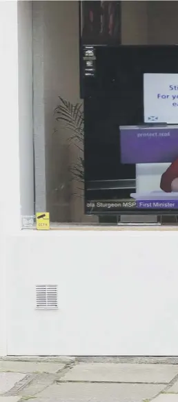  ??  ?? 0 A member of the public walks past a television screen in a shop in Edinburgh as First Minister Nicola Sturgeon took part in a virtual sitting of Holyrood after the latest on measures to combat coronaviru­s were announced