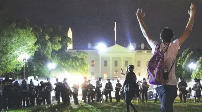  ??  ?? A protestor holds his hands up as police officers enter Lafayette Park to keep demonstrat­ors away from the White House during a protest in Washington DC, US, on Thursday night. — Reuters