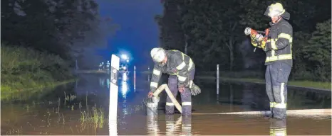  ?? FOTOS: THOMAS WARNACK ?? Unwetter am Mittwochab­end: Feuerwehrl­eute müssen das Wasser auf der überflutet­en Straße zwischen Moosheim und Großtissen abpumpen. Mehrere Stunden sind die Einsatzkrä­fte unterwegs.