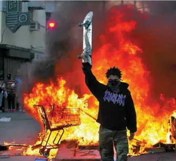  ??  ?? Un manifestan­te sostiene un patinete junto a un incendio en Los Angeles. A la derecha, otra protesta en Minesota contra la muerte del afroameric­ano George Floyd a manos de la Policía
