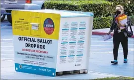  ?? Irfan Khan Los Angeles Times ?? A WOMAN prepares to put her ballot in a drop box in Norwalk. The pandemic caused the Legislatur­e to pass a law in 2021 to send mail-in ballots to all voters.