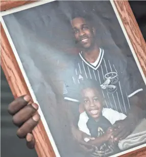  ?? MORALES FOR MLK50 ANDREA ?? Leanell “Troy” Mcclenton holds a photograph of his son, Duntate Young, with Young’s oldest son, Jaydon Ellis. Young died on Jaydon’s sixth birthday.